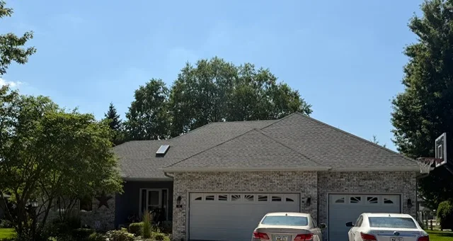 New charcoal gray asphalt shingle roof on brick residential home with hip design